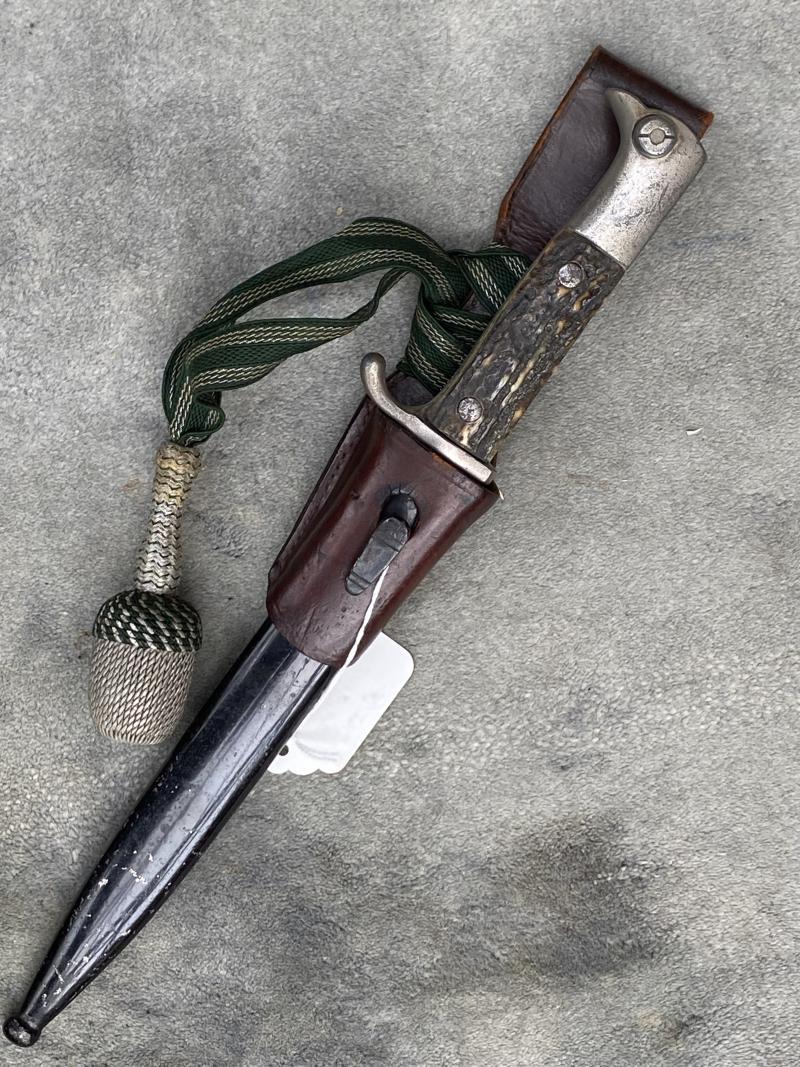 A SHORT LUFTWAFFE PARATROOPER K98 DRESS BAYONET WITH STAG GRIPS, FROG AND NCO’s PORTAPEE.